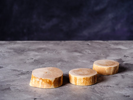 Slices of wood of tree for product presentation lies on a gray concrete surfaceの写真素材