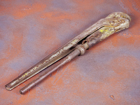 Old rusty adjustable spanner on a grunge orange backgroundの写真素材