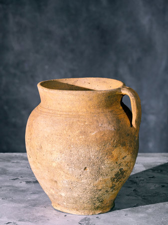 Vintage shabby clay jug with handle on a gray concrete surfaceの写真素材
