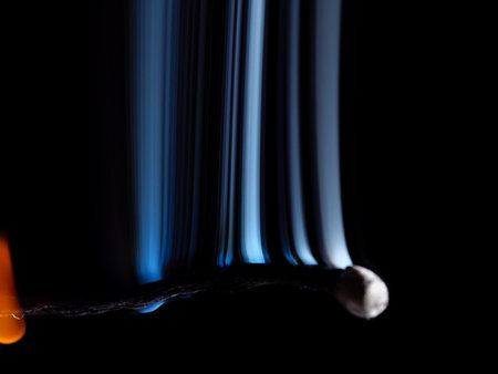 Burned matchstick with white smoke jets rising isolated on a black backgroundの写真素材