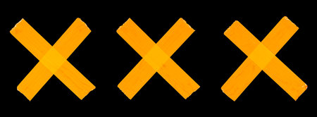 Cross-folded crosses of orange adhesive tape isolated on a black backgroundの写真素材