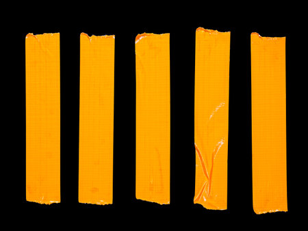 5 vertical pieces of orange adhesive tape isolated on a black backgroundの写真素材