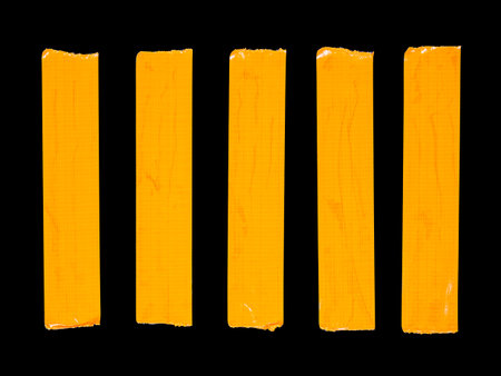 5 vertical pieces of orange adhesive tape isolated on a black backgroundの写真素材