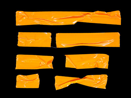 A set of various pieces of orange masking tape isolated on a black backgroundの写真素材