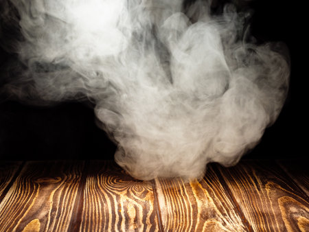 Tubes of white smoke over a wooden board as a background for product presentationの写真素材
