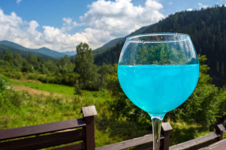 glasses with blue champagne against the background of the mountains.の写真素材