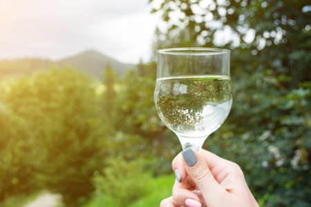 a glass of wine with an inverted image in the girl's hand, against the backdrop of mountains and coniferous forests.の写真素材
