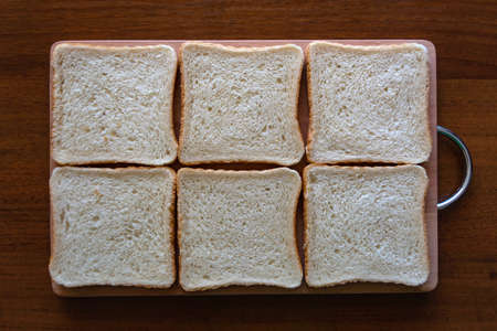 Wooden board with tasty toasted bread on tableの写真素材