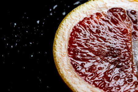 grapefruit pulp with drops of moisture on a black mirror.の写真素材