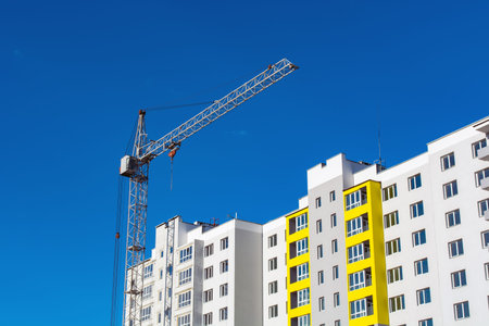 Crane and building construction site against blue sky.