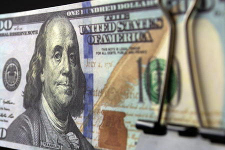 a bundle of hundred-dollar bills compressed by a binder.
