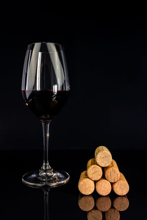 red wine in a glass on a high leg on a black background.の写真素材
