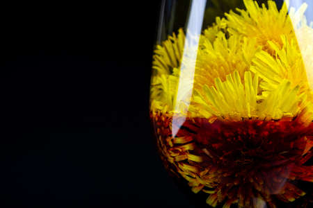 red wine from dandelions in a glass on a black background.の写真素材