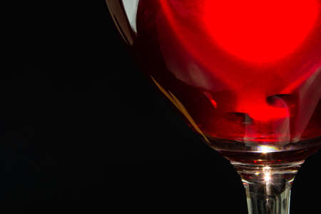 red wine in a glass on a high leg on a black background.の写真素材
