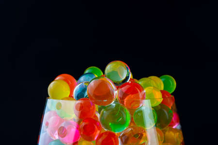 multi-colored silicone gel balls in a glass on a black background.の写真素材