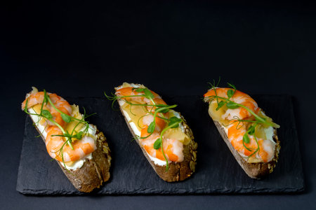 fresh bruschetta with shrimp, cheese, ham and microgreens.の写真素材