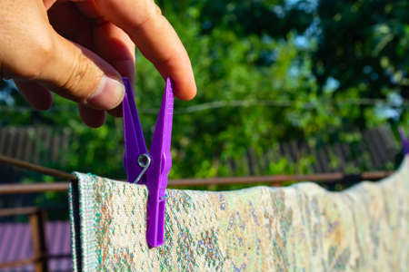 girl hooks clothes on a rope with clothespins.の写真素材
