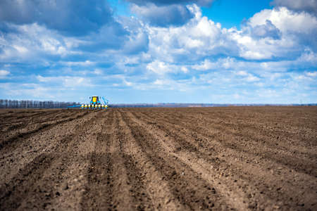 sowing work in the field in spring. Tractor with seeder.の写真素材