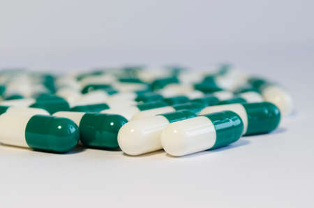 Green and white capsules on a light background.の写真素材