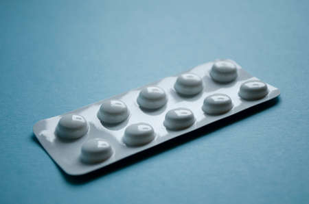 Ten pills in blister pack close-up on blue background.の写真素材