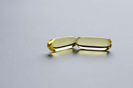 Two yellow transparent capsules on light background.の写真素材