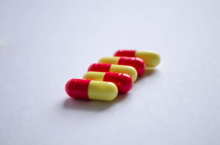 Five red and yellow capsules on a light background.の写真素材