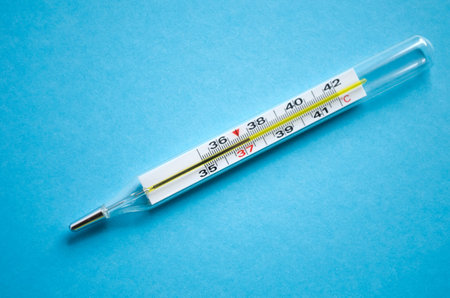 Mercury thermometer shows subfebrile temperature on a blue background.の写真素材