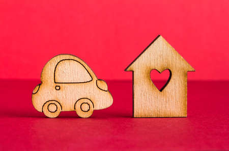 Wooden house with hole in the form of heart with wooden car icon on red background.の写真素材