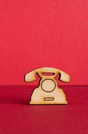 Wooden icon of telephone on red background vertical.の写真素材