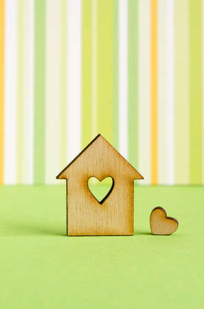 Wooden house with hole in the form of heart with  little heart on green striped background verticalの写真素材