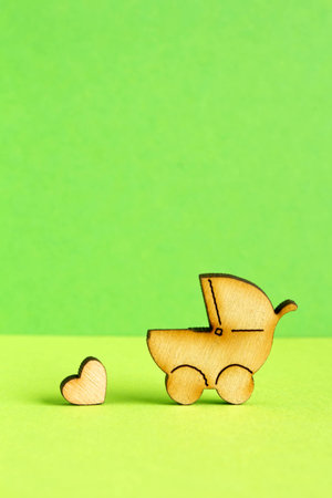 Wooden icon of baby carriage and little heart on green background verticalの写真素材