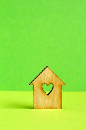 Wooden house with hole in the form of heart on green background verticalの写真素材