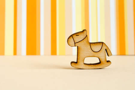 Wooden icon of children's rocking horse on orange striped background horizontalの写真素材