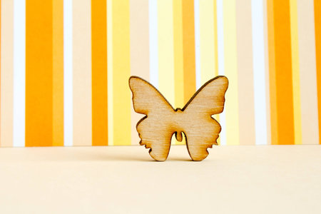Wooden icon of butterfly on orange striped background horizontalの写真素材