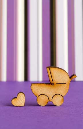 Wooden icon of baby carriage and little heart on purple striped background verticalの写真素材