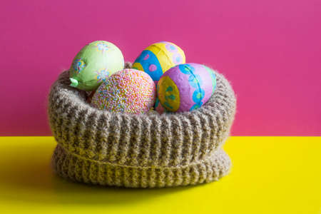 Multi-colored Easter eggs in knitted basket.の写真素材
