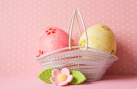 Pink and yellow Easter eggs in a basket with pink flower.