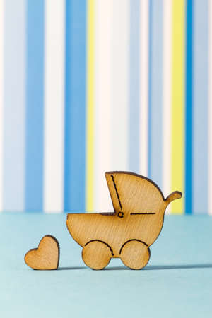 Wooden icon of baby carriage and little heart on blue striped background verticalの写真素材