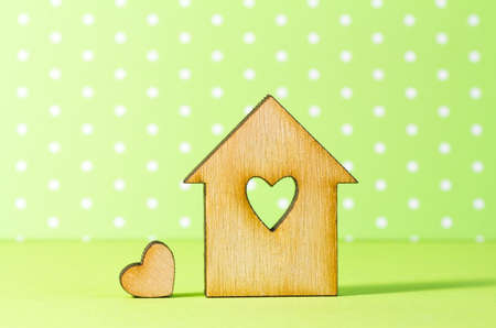 Wooden house with hole in the form of heart with little heart on green background.の写真素材