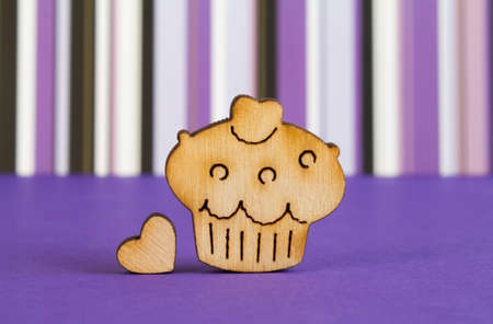 Wooden icon of cake with little heart on purple striped background.の写真素材