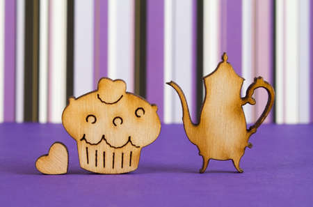 Wooden icons of cake and teapot with little heart on purple striped background.の写真素材