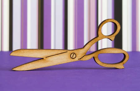Wooden icon of scissors on purple striped background.の写真素材