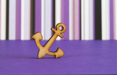 Wooden icon of anchor on purple striped background.の写真素材