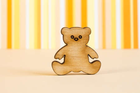 Wooden icon of Teddy bear on orange striped background.の写真素材