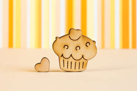 Wooden icon of cake with little heart on orange striped background.の写真素材
