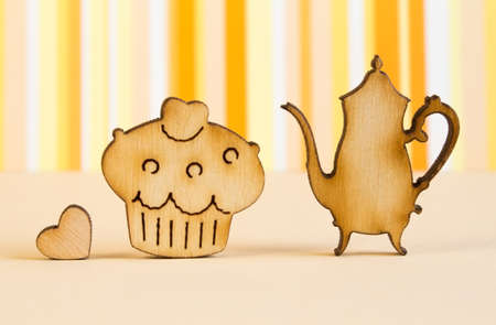 Wooden icons of cake and teapot with little heart on orange striped background.の写真素材