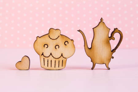 Wooden icons of cake and teapot with little heart on pink background.の写真素材