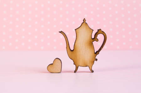 Wooden icon of teapot with little heart on pink background.の写真素材