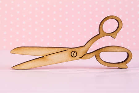 Wooden icon of scissors on pink background.の写真素材