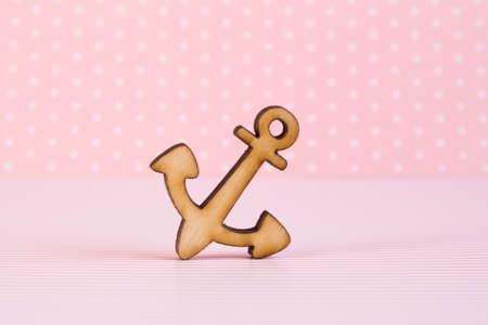 Wooden icon of anchor on pink background.の写真素材